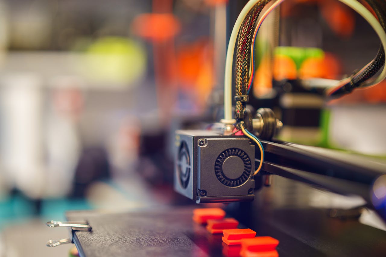 Detailed close-up of a 3D printer extruding red plastic during operation.
